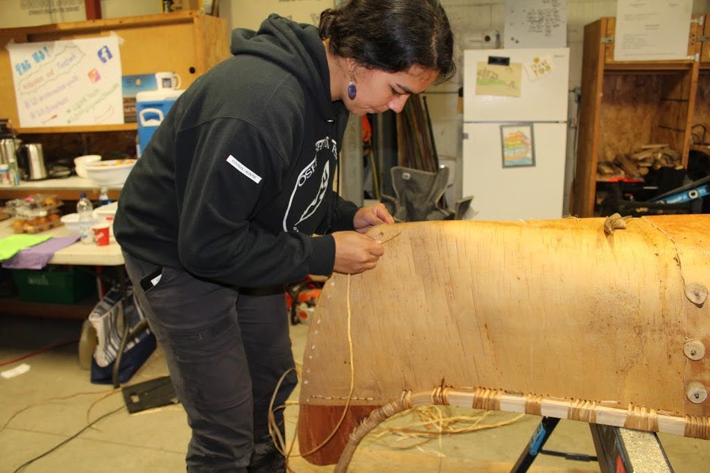 Kyla stitching the bow or stern using spruce root